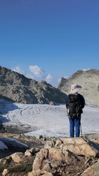 Hiker With Backpack Overlooks Majestic Glacier And Mountains In British Columbia, Canada