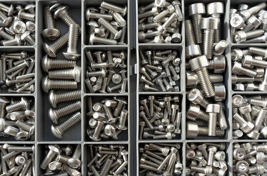 Metal fasteners organized in box compartments, industrial background pattern