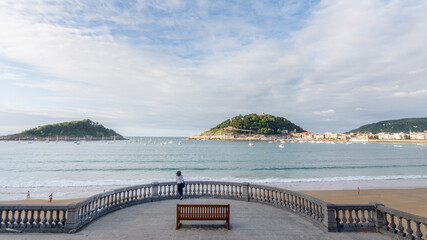 Naklejka premium Woman enjoying the view of La Concha Bay in San Sebastian, Basque Country, Spain.