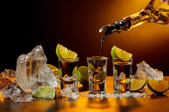 The tequila is poured from the bottle into shot glasses.
