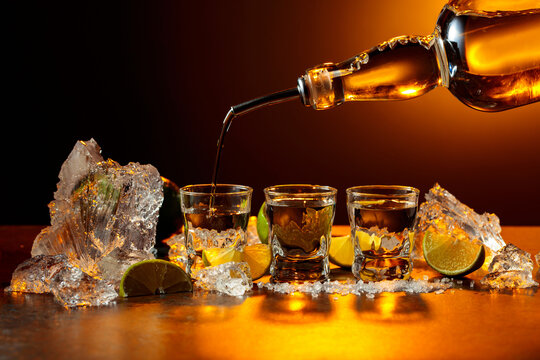 The tequila is poured from the bottle into shot glasses.