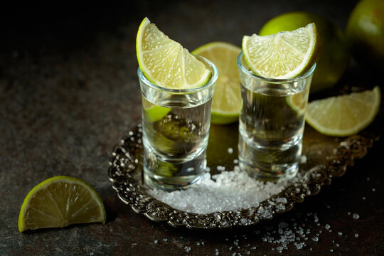 Tequila with salt and lime slices on a silver tray.