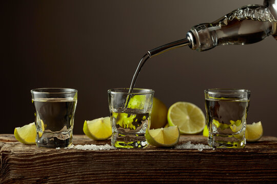 Tequila with salt and lime slices on a old wooden board.