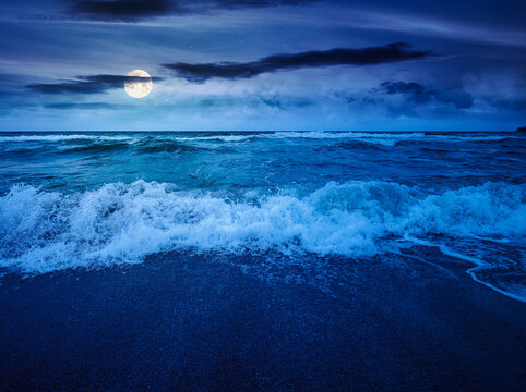 storm on the sandy beach at night. wonderful sea view with cloudy sky. full moon over salt water and crashing waves. mysterious view of bulgaria beach in summer. wind weather background