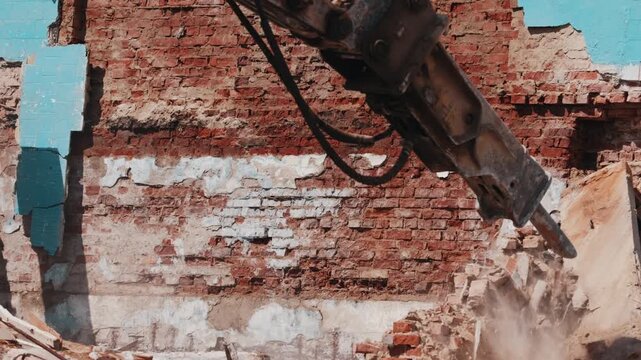 Excavator hydraulic hammer demolishing brick wall during construction work