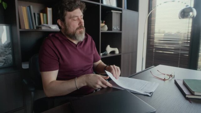 Medium shot of male Caucasian author proofreading novel draft, getting dissatisfied, crumpling printed copy and throwing it away, creative block concept