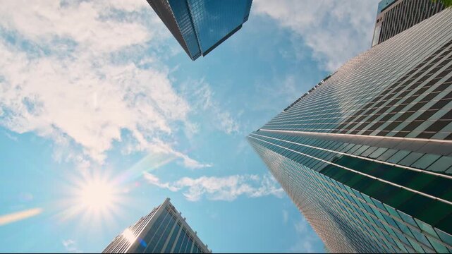 Timelapse Modern three skyscrapers glass facade buildings with sun flare from low angle view. Business district architecture finance growth south-east asia corporate urban skyline with clouds passing