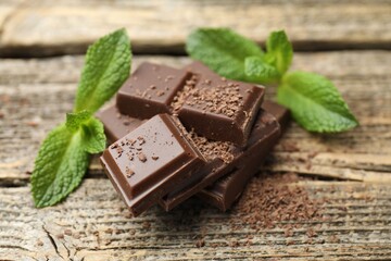 Pieces of yummy chocolate and mint leaves on wooden table, closeup © New Africa