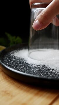 Rimming cocktail glass with sugar, creating perfect drink garnish, bartender technique, drink decoration, cocktail preparation.