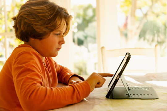 12 year old boy using tablet at home at sunset