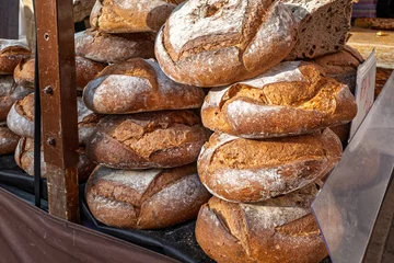 Fototapeten Brot Stack Of Rustic Artisan Bread Loaves At Market Stall  © Manuel
