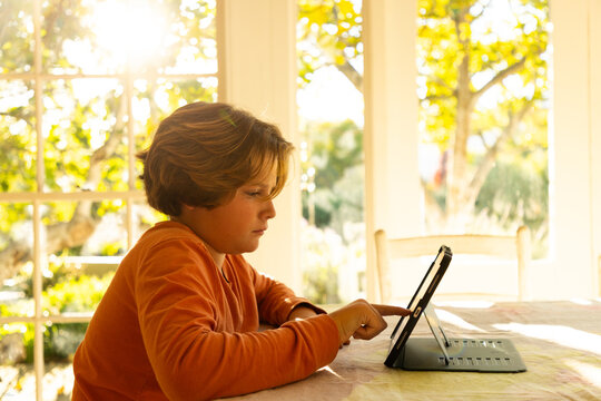 12 year old boy using tablet at home at sunset