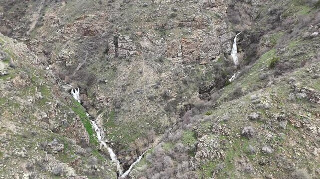 4K aerial drone footage of multiple waterfalls in rocky mountain canyon with streams and natural landscape.