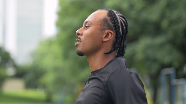 Young Black Latin man in sportswear doing jumping jacks cardio exercise with motion blur in urban park outdoors daytime