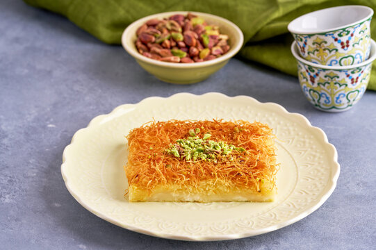 Traditional middle eastern cheese kunafa dessert . Turkish, arabic traditional sweets. Served with sugar syrup and pistachio