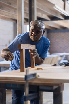 wooden components being aligned on bench in carpentry workshop with clamp and handsaw nearby
