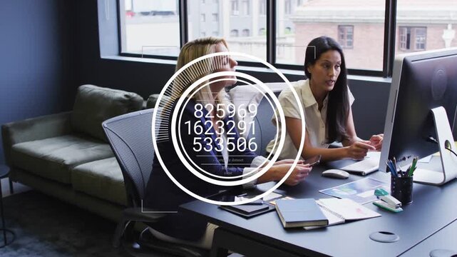 Two business women clicking mouse and pointing at screen, analyzing data with ring overlay updating