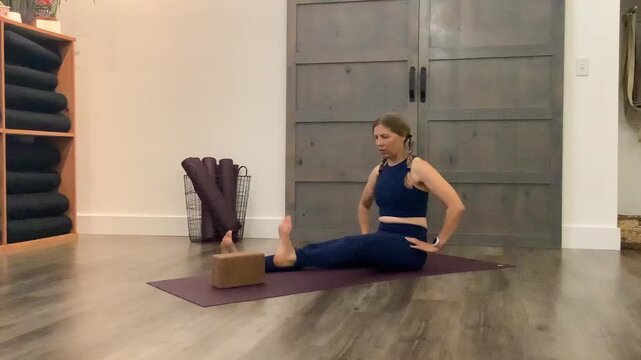 woman doing leg lifts over blocks on yoga mat in studio