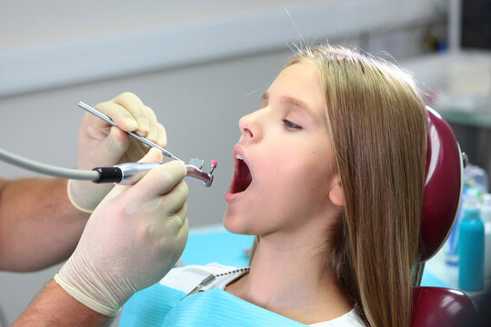 Pretty teenage girl with long hair at dentist appointment. Brushing your teeth. Prevention of caries. Concept of healthcare