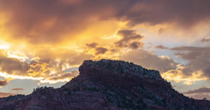 Golden light washes over the red rock mountain