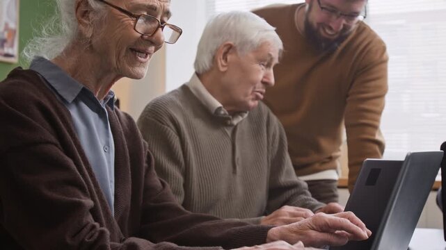 Side view shot of smiling senior woman using laptop in computer literacy class with focus flowing from face to hands typing on keyboard, copy space