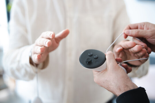 Two people are interacting with a virtual reality controller, one person is holding the device while the other gestures.