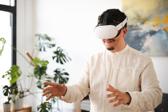 A man wearing a virtual reality headset gestures with his hands while experiencing an immersive digital world.