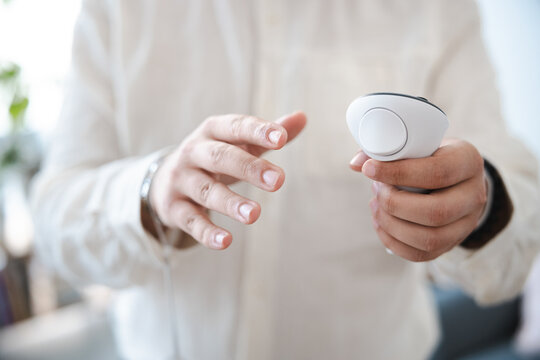 A person in a white shirt holds a white controller, ready to interact with technology.