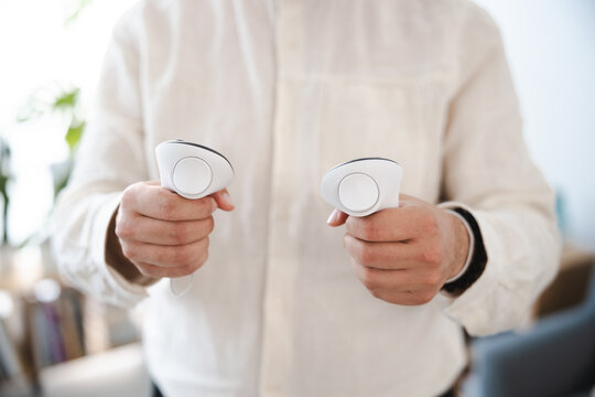 A person in a light colored shirt holds two white controllers, ready to engage in a virtual reality experience.