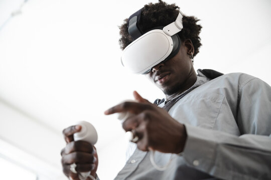 A young man wearing a virtual reality headset and holding controllers engages with immersive digital content.