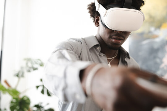 A young man wearing a virtual reality headset interacts with a digital world, his hand reaching out to touch something unseen.