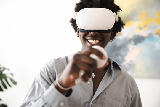A smiling man wearing a virtual reality headset and holding a controller, immersed in a digital world.
