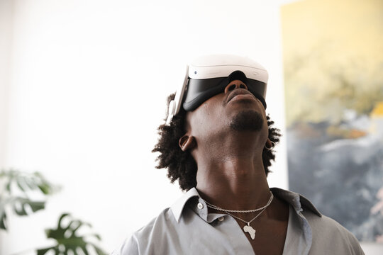 A man wearing a virtual reality headset looks upwards, experiencing an immersive digital world.