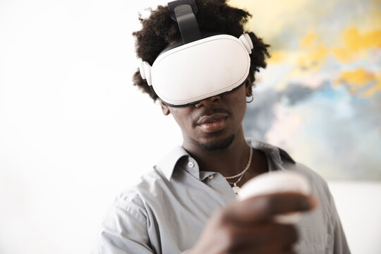 A young man wearing a virtual reality headset and holding a controller engages with immersive digital content, exploring new virtual worlds.