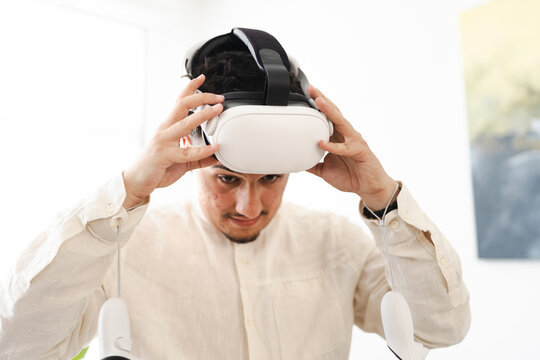 A young man adjusts his virtual reality headset, preparing to enter an immersive digital world.