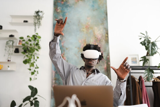 A man wearing a virtual reality headset interacts with a digital world, his hands gesturing as he engages with immersive technology.