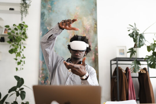 A man wearing a virtual reality headset interacts with a digital interface, his hands gesturing as he navigates a virtual world.