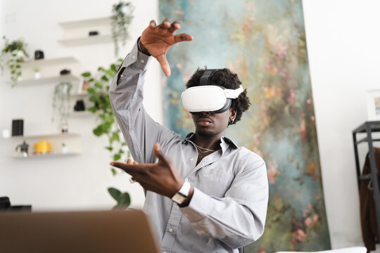 A young man wearing a virtual reality headset gestures with his hands as he experiences an immersive digital world.