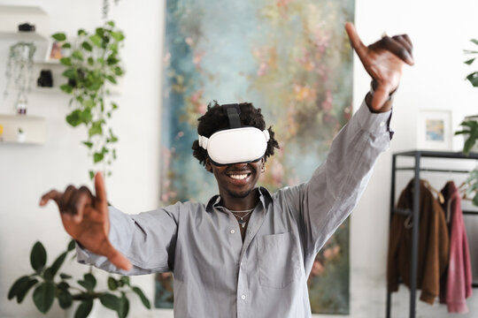 A smiling man wearing a virtual reality headset interacts with a digital world, his arms outstretched in a dynamic pose.
