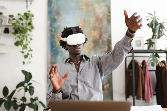 A young man wearing a virtual reality headset interacts with a digital world, his hands gesturing as he explores an immersive experience.