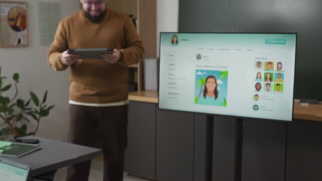 Tilt up shot of male teacher giving lecture standing by digital board with mock social media page explaining internet communication to group of adult students in computer literacy class, copy space