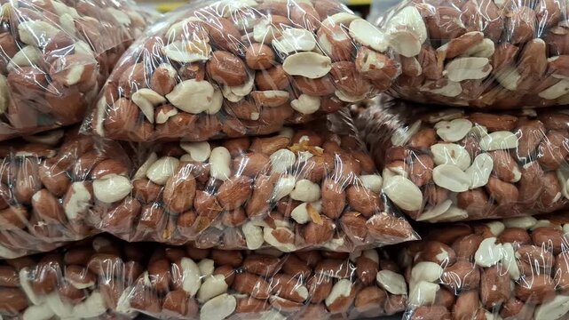 Close-up of raw peanuts packed in clear polyethylene bags for retail sale. Healthy food for proper nutrition. Snack production, distribution, and calorie-dense food storage or retail
