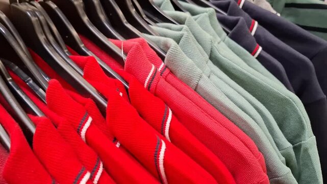 Colorful selection of mens polo shirts on hangers in retail clothing store. Vibrant red, yellow and blue piqu&eacute; fabrics. Display casual style fashion. Texture of knit fabric, variety of bright colors