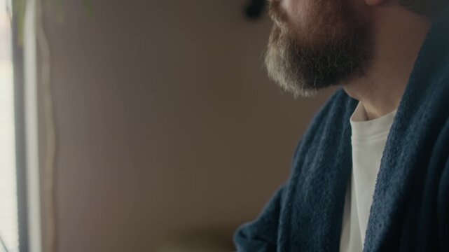 Close up tilt up of middle aged Caucasian male writer in eyeglasses holding pencil in hand procrastinating while sitting indoors