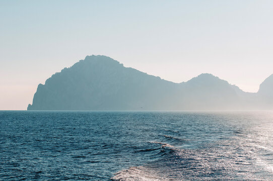 View of a Mountain in the Distance With Water in the Foreground on a Clear Day During Morning Hours