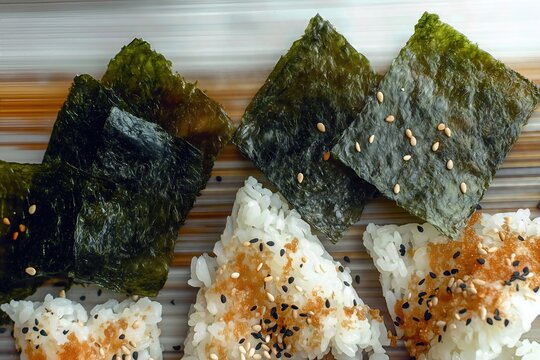 Top-down view of triangular onigiri rice balls seasoned with sesame seeds, placed next to crispy green nori seaweed sheets.
