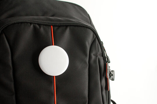 Round badge mockup close up. Black backpack fabric texture. Blank button pin template. Detailed rucksack branding. White circle on bag. Angled merch display. Red line accent shot. Minimalist textile