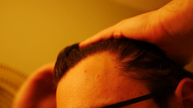 A Man applies Pomade or Hair Product to his Hair