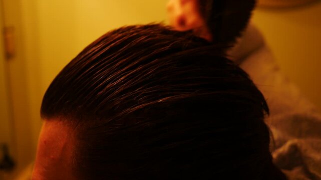 A Man Combs his Gelled Hair with a Brush