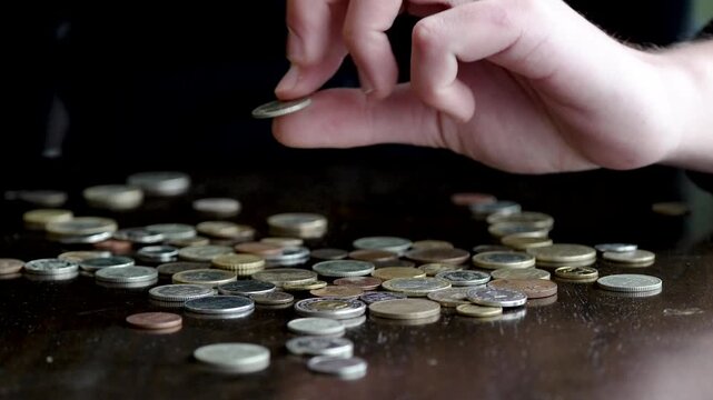 Person sorting through coins on a table, searching for a specific rare coin
